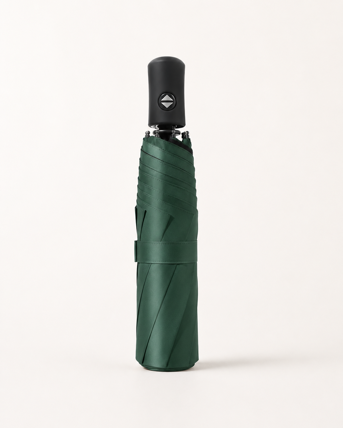 A folded dark green umbrella with a black handle, standing upright against a clean, off-white background.